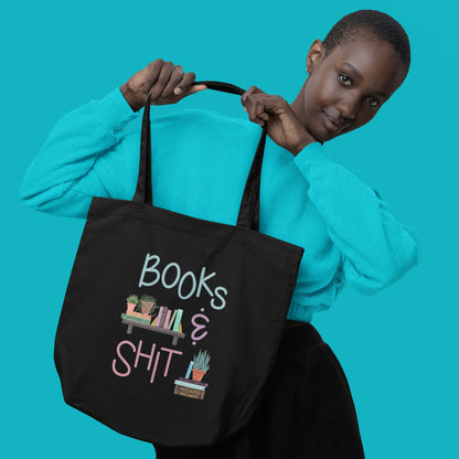 Product image of Moxie•Pop's eco tote bag with "Books & Shit" with books and house plants artwork in black with female with short hair holding the tote