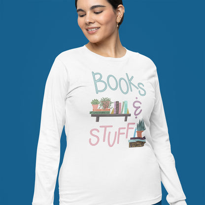 Modeled product image of Moxie•Pop's men's long sleeve graphic tee with hand lettered "books & stuff" with hand-drawn books with potted house plants design in white