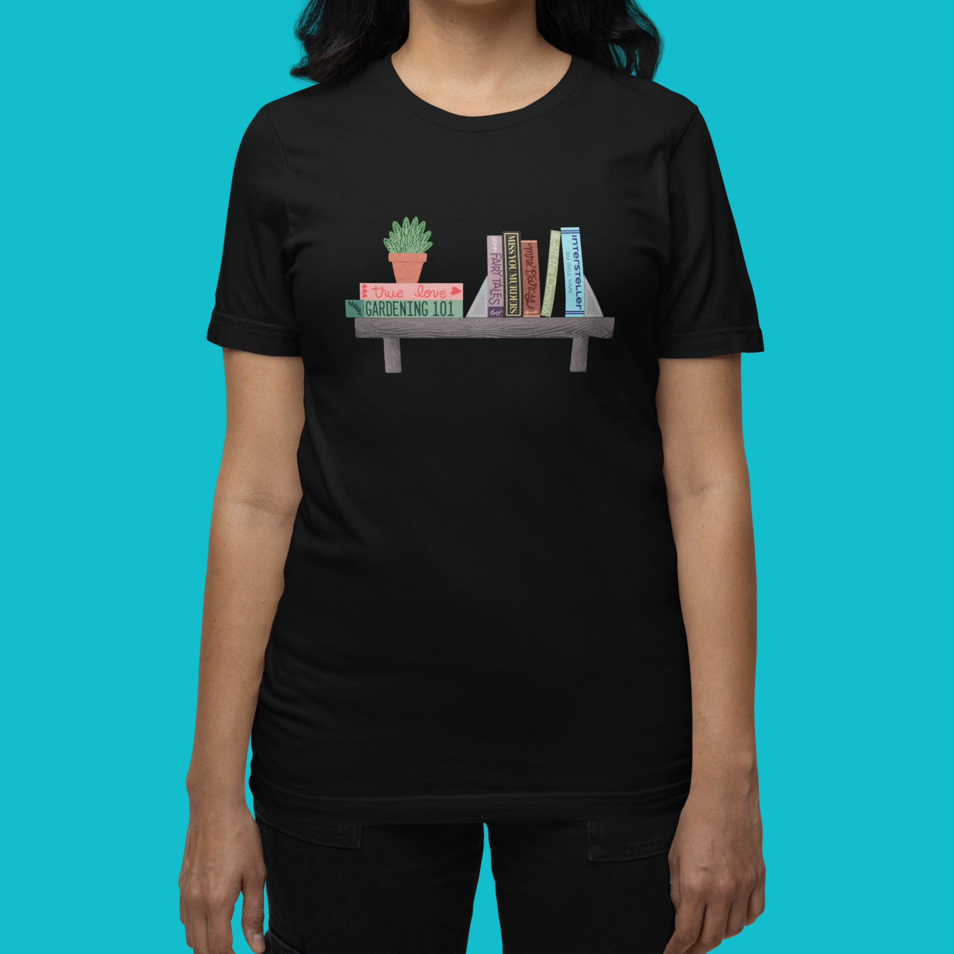 Modeled product image of Moxie•Pop's unisex graphic tee with hand drawn bookshelf holding stacks of books and house plants artwork in black heather