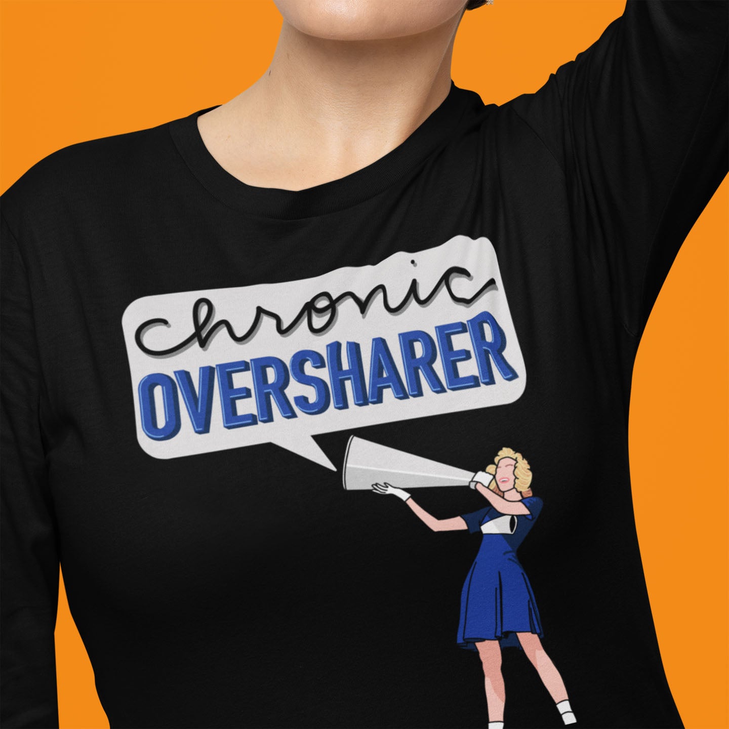 Modeled product image of Moxie•Pop's men's long sleeve graphic tee with a illustration of a vintage cheerleader yelling into a megaphone with a talk bubble announcing 'Chronic Oversharer' in black