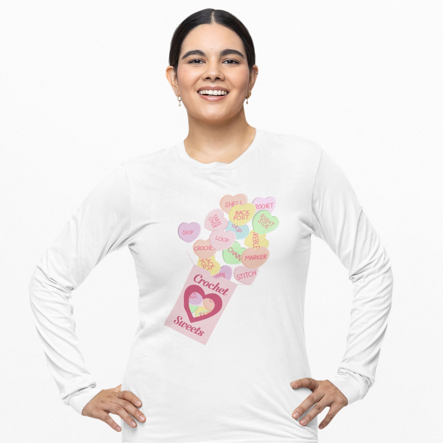 Modeled product image of Moxie•Pop's men's long sleeve graphic tee with a box of "Crochet Sweets" and conversation hearts with crocheting terms design in white