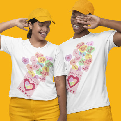 Modeled product image of Moxie•Pop's unisex graphic tee with Valentine's conversation hearts with quotes from the Friends TV show and a box that reads "Friends Love" in white. Models are wearing yellow baseball hats, and yellow pants, in front of a yellow background