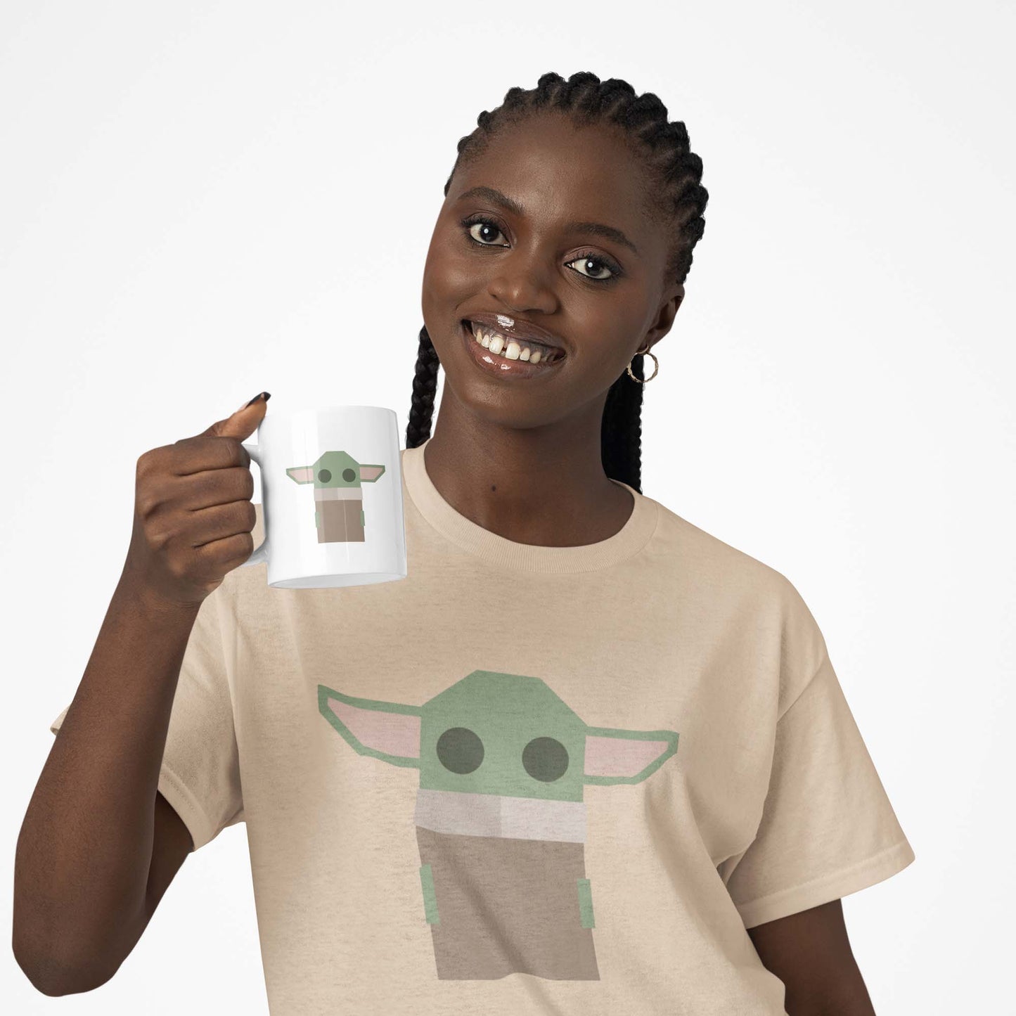 Moxie•Pop's white ceramic mug with a geometric-styled Grogu modeled by a woman with long braids wearing a 'Grogu' tee in soft cream with a white backdrop