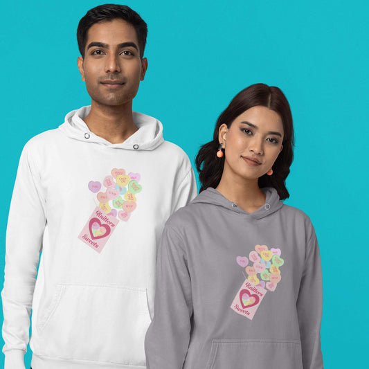 Moxie•Pop's unisex graphic hoodie with a box of "Knitter Sweets" and Valentine's conversation hearts with knitting terms design in sport grey and white being modeled by a man and a woman with a turquoise backdrop. 