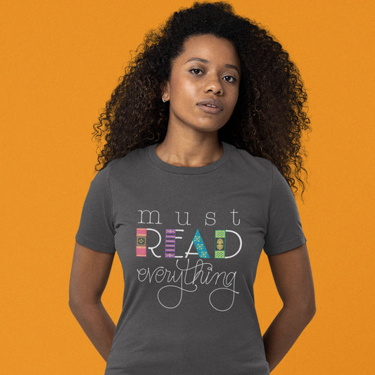 Modeled product image of Moxie•Pop's unisex graphic tee with "must Read everything" with the downstroke of 'read' hand drawn to look like book spines. 