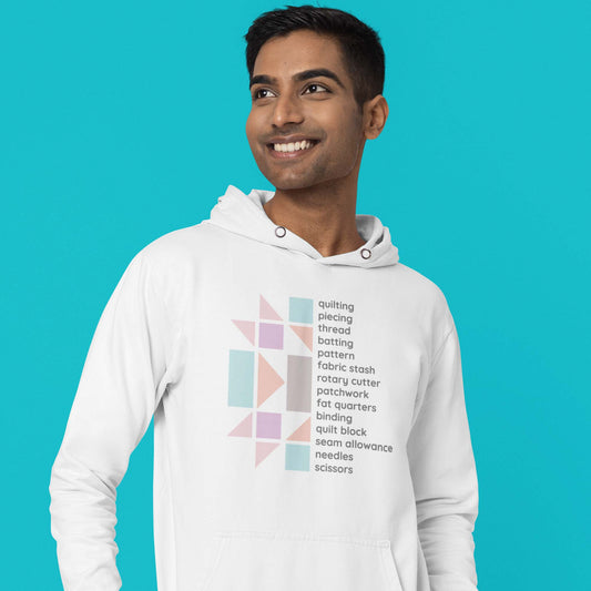 Moxie•Pop's unisex graphic hoodie with a design of half a pastel quilt block and a list of quilting terms in white modeled by a man with a turquoise backdrop