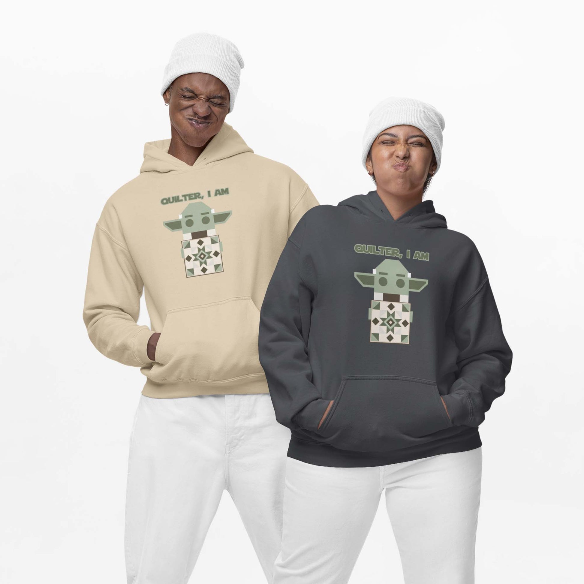 Moxie•Pop's unisex graphic hoodie with a geometric Yoda holding a quilt with the phrase "Quilter, I am" design in dark heather and sand being modeled by a man and a woman wearing white beanies and white sweatpants with a white backdrop