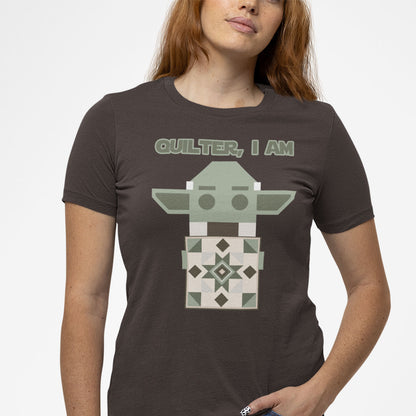 Modeled product image of Moxie•Pop's unisex graphic tee with a geometric Yoda holding a quilt with the phrase "Quilter, I am" design in brown