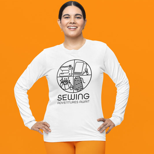 Modeled product image of Moxie•Pop's men's long sleeve graphic tee with a minimalist design of sewing icons and the phrase "Sewing Adventures Await" design in white. Model is wearing orange pants and is standing in front of an orange backdrop. 