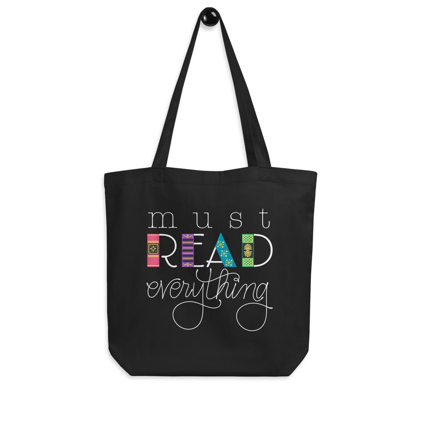 Hanging product image of Moxie•Pop's eco tote bag with hand lettered "must READ everything" with the downstrokes of the word 'read' drawn to look like book spines in black. 