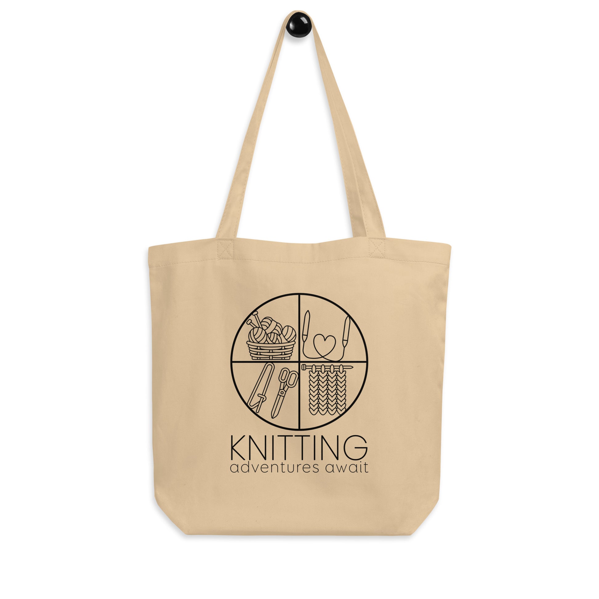 Hanging product image of Moxie•Pop's eco tote bag with "KNITTING adventures await" below a circle filled with knitting implements icons design in oyster