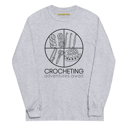 Lay flat product image of Moxie•Pop's mens' long sleeve graphic tee with "CROCHETING adventures await" below a circle filled with crocheting implements icons design in sport grey