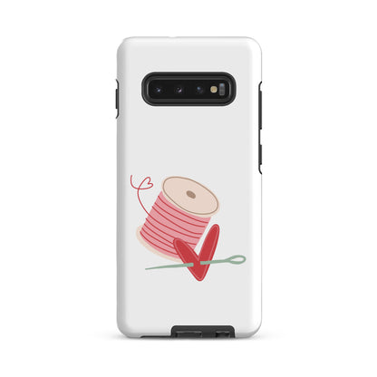 Product image of Moxie•Pop's tough case for Samsung® with a hand-drawn spool of pink thread and a heart pierced by a needle on a Galaxy S10 Plus