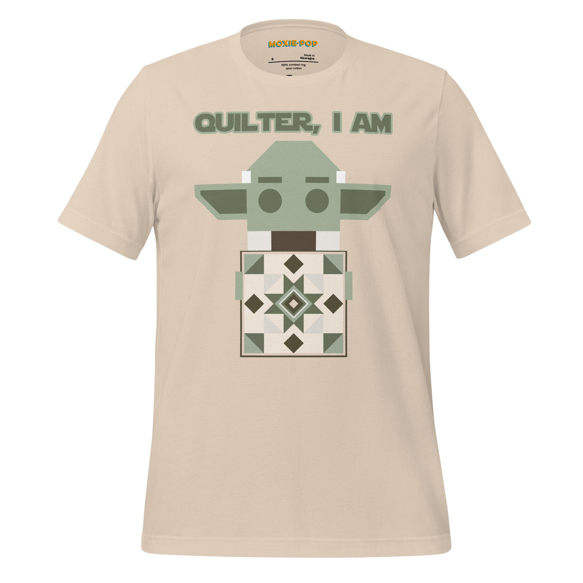 Lay flat product image of Moxie•Pop's unisex graphic tee with a geometric Yoda holding a quilt with the phrase "Quilter, I am" design in soft cream