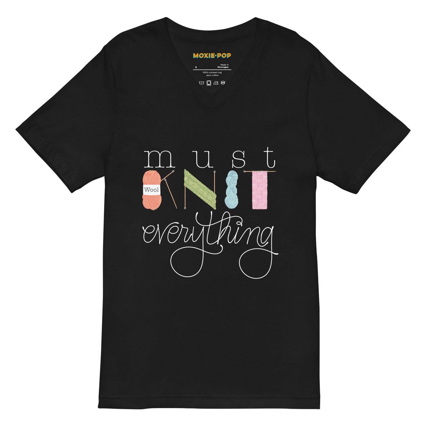 Lay flat product image of Moxie•Pop's unisex v-neck tee with hand lettered "must KNIT everything" with the downstrokes of the word 'KNIT' hand drawn yarn, knitting needles, and knitted scarves in black