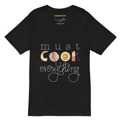 Lay flat product image of Moxie•Pop's unisex v-neck graphic tee with hand lettered 'must cook everything' with the word cook created from hand drawn food items in black