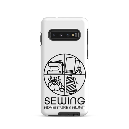 Moxie•Pop's tough case on a Samsung® in white with a black image of a circle in four quadrants each with a sewing tool icon above 'Sewing Adventures Await'. 